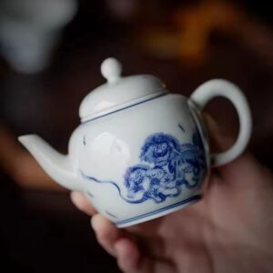 Bule de porcelana chinês ornamentado com leões, visto na mão